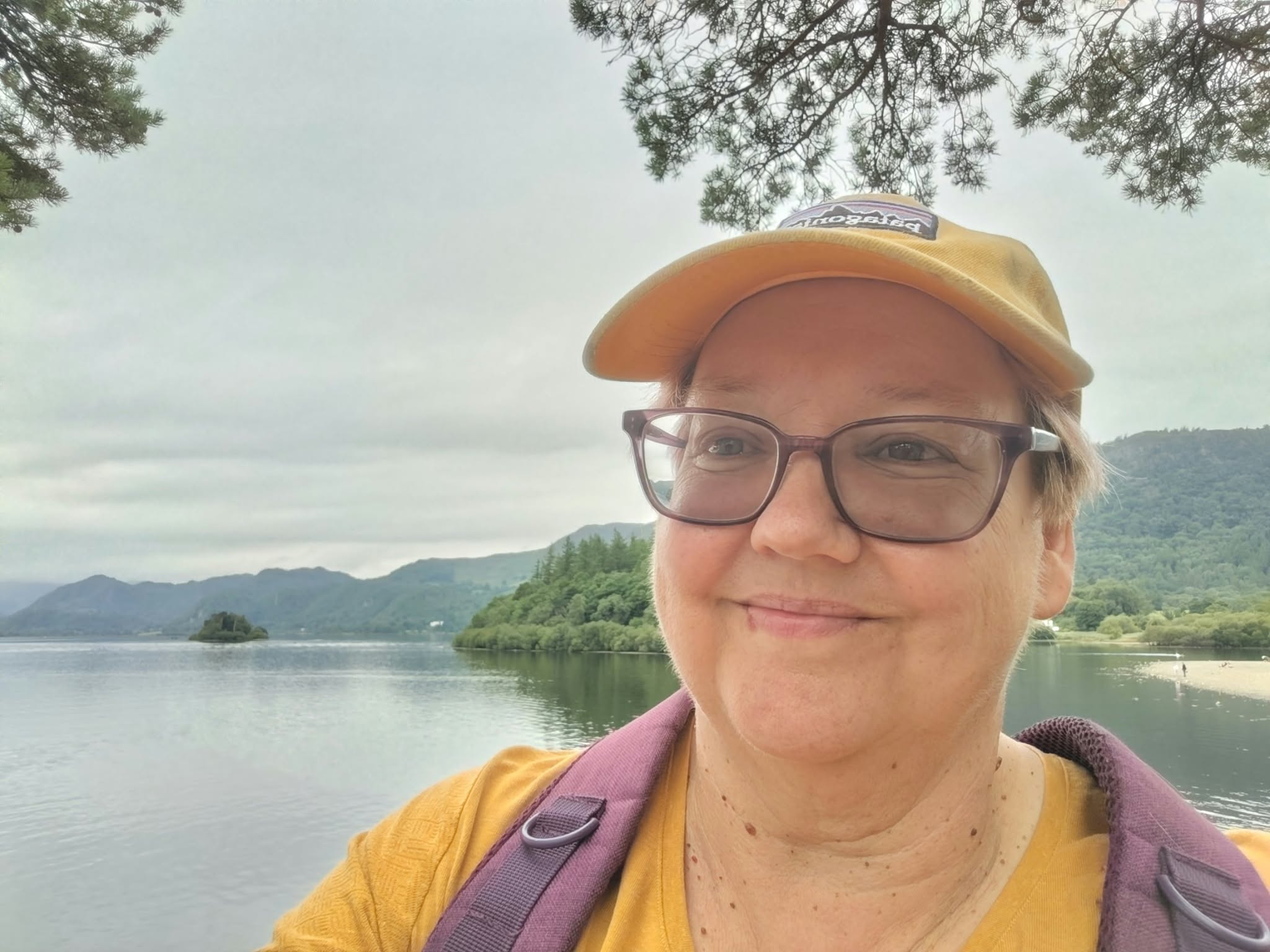 Marnie beside a lake, with woodland and hills behind her